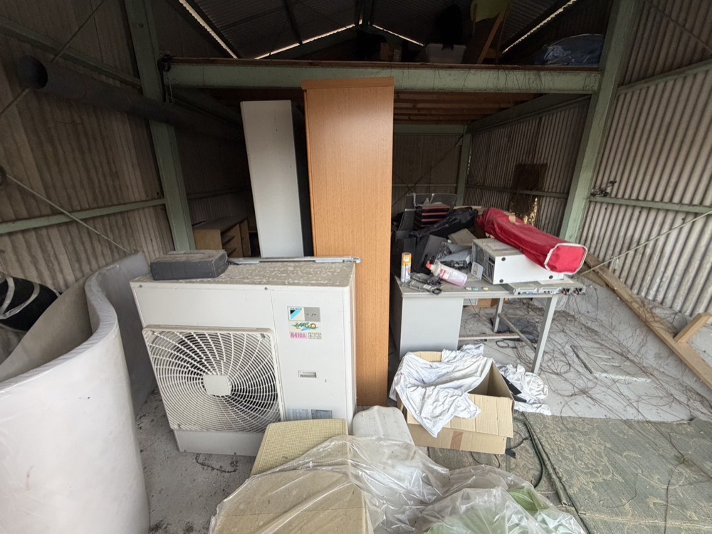 倉庫・物置の片づけ前。家具や家電が積み上がった状態