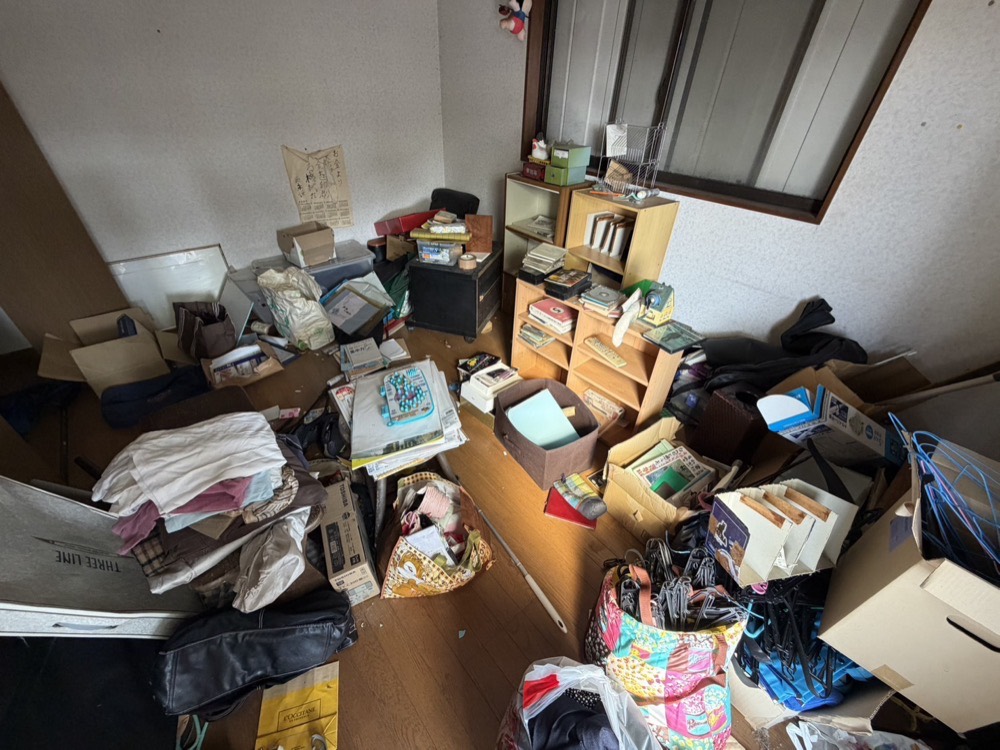 お部屋の片づけ前。衣類や本、雑貨が床に広がった状態